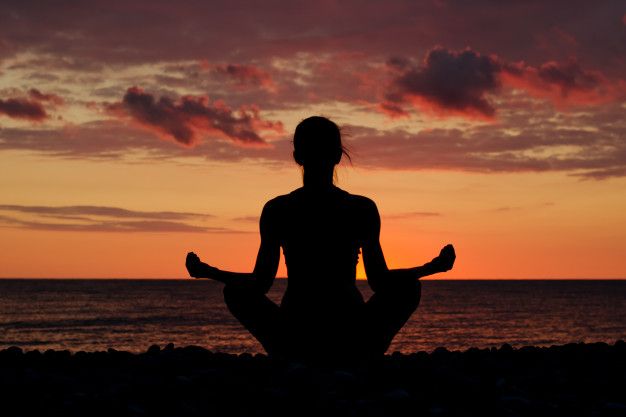 pessoa meditando em uma praia ao amanhecer