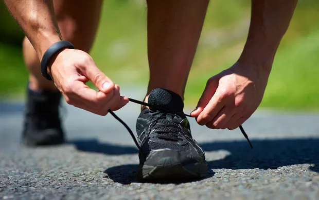 Alguém amarrando o cadarço do tênis de corrida