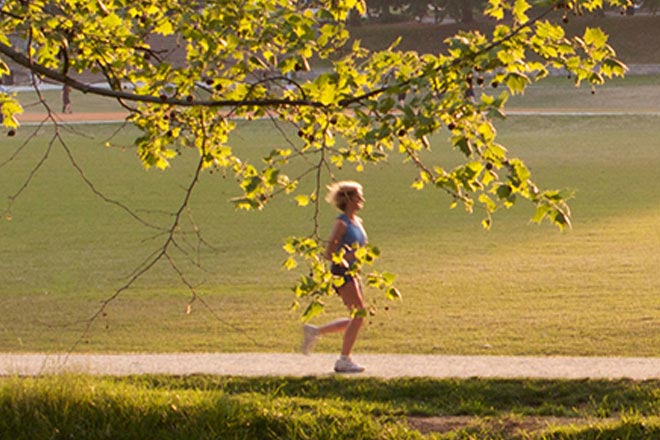 pessoa correndo em um parque, com a natureza ao fundo